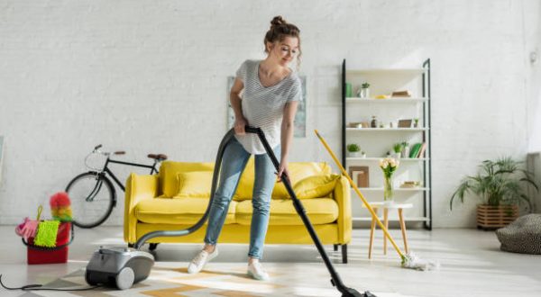happy girl cleaning carpet with vacuum cleaner